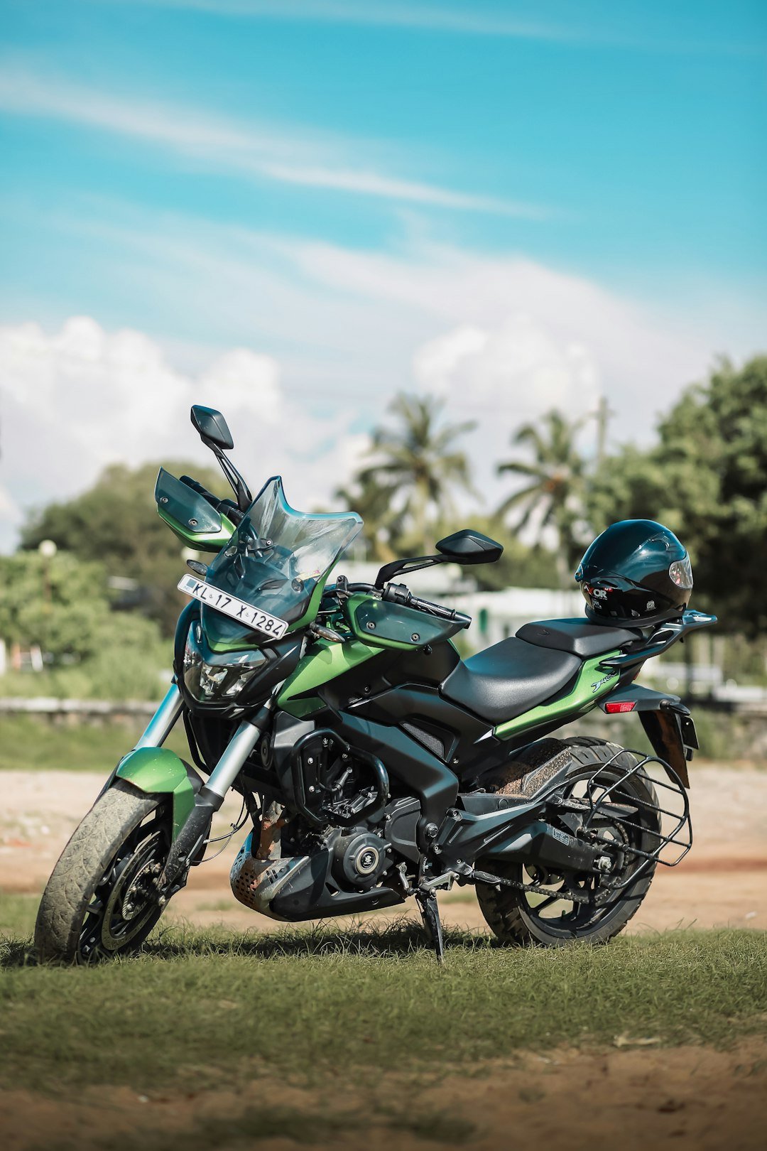 A green motorcycle parked on top of a lush green field