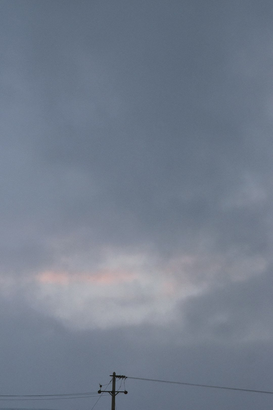 an airplane flying high in the sky with power lines in the foreground