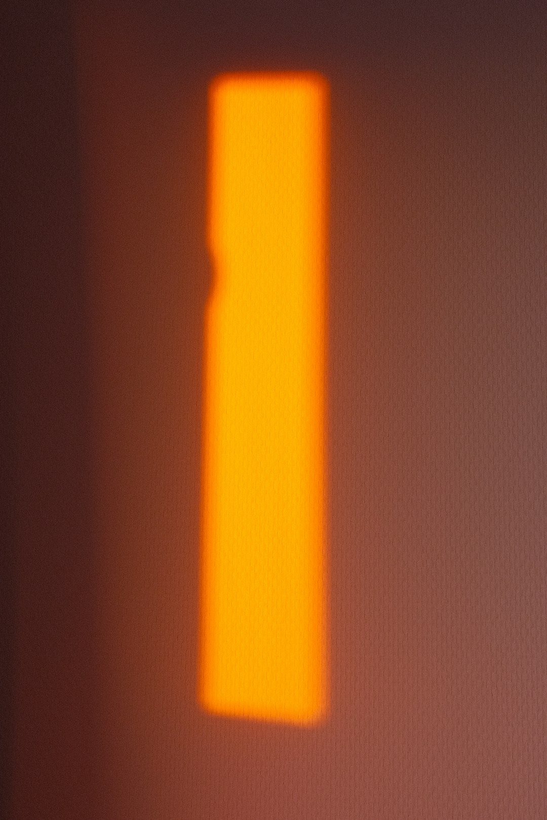 A bright orange rectangle glows against a wall.