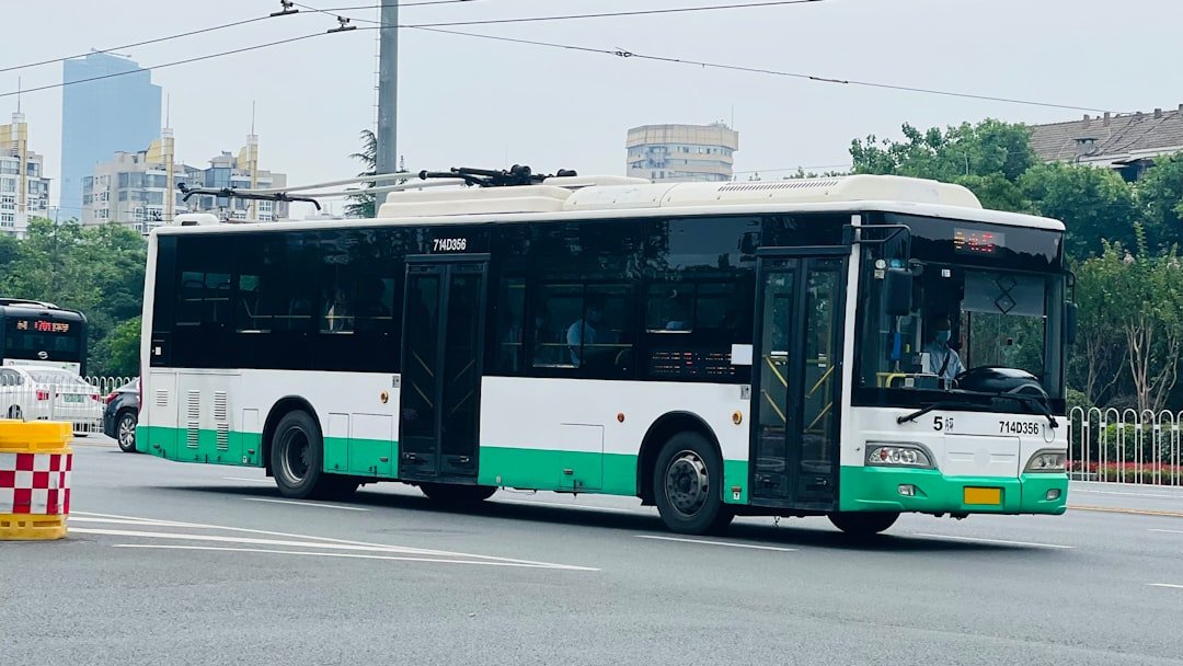 a green and white bus driving down a street