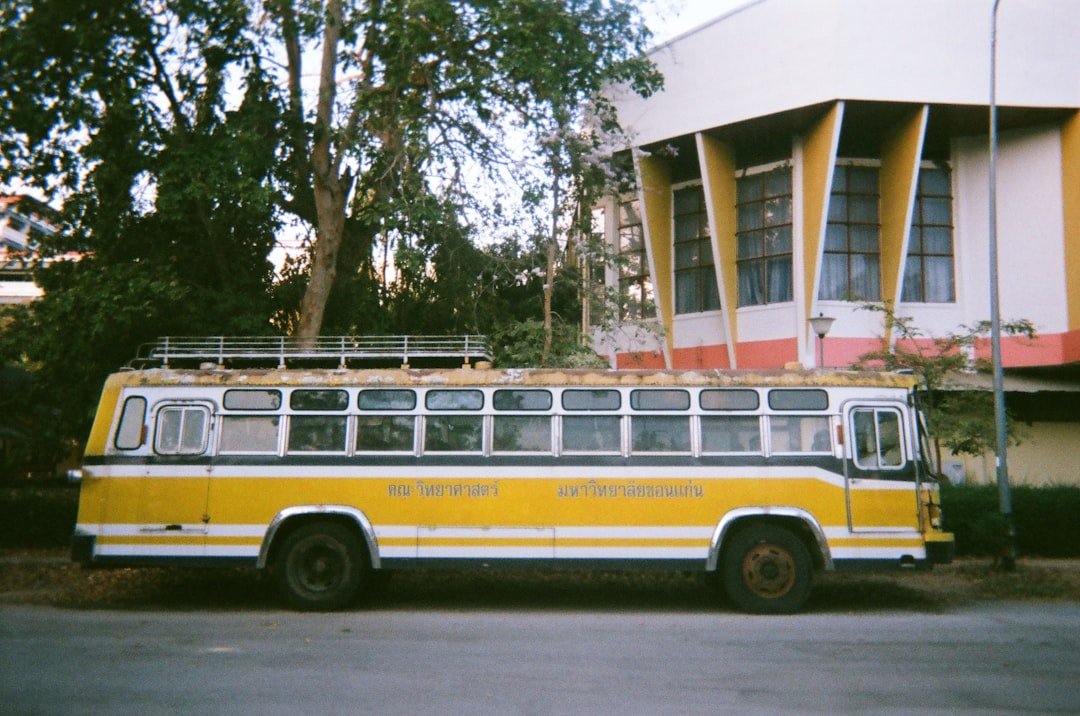 a yellow and white bus parked in front of a building