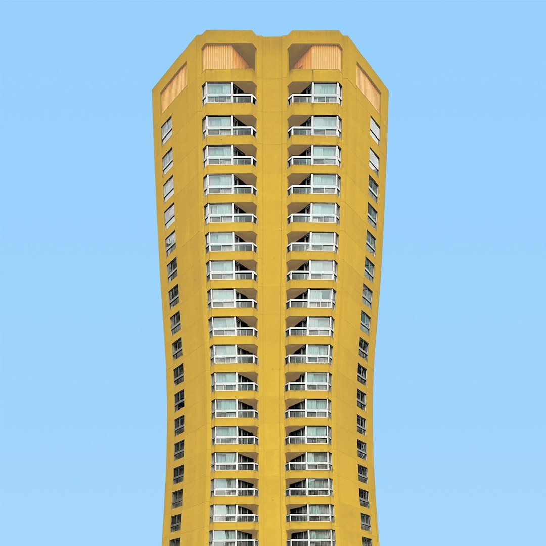a tall yellow building with balconies on the windows