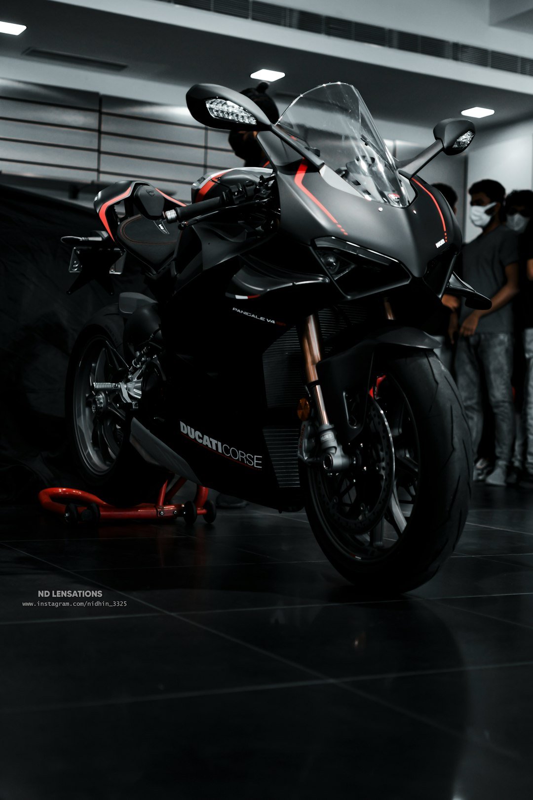 a black motorcycle parked in a garage next to a group of people