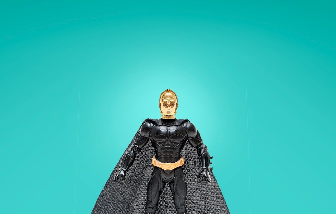 a batman action figure standing on top of a black cape