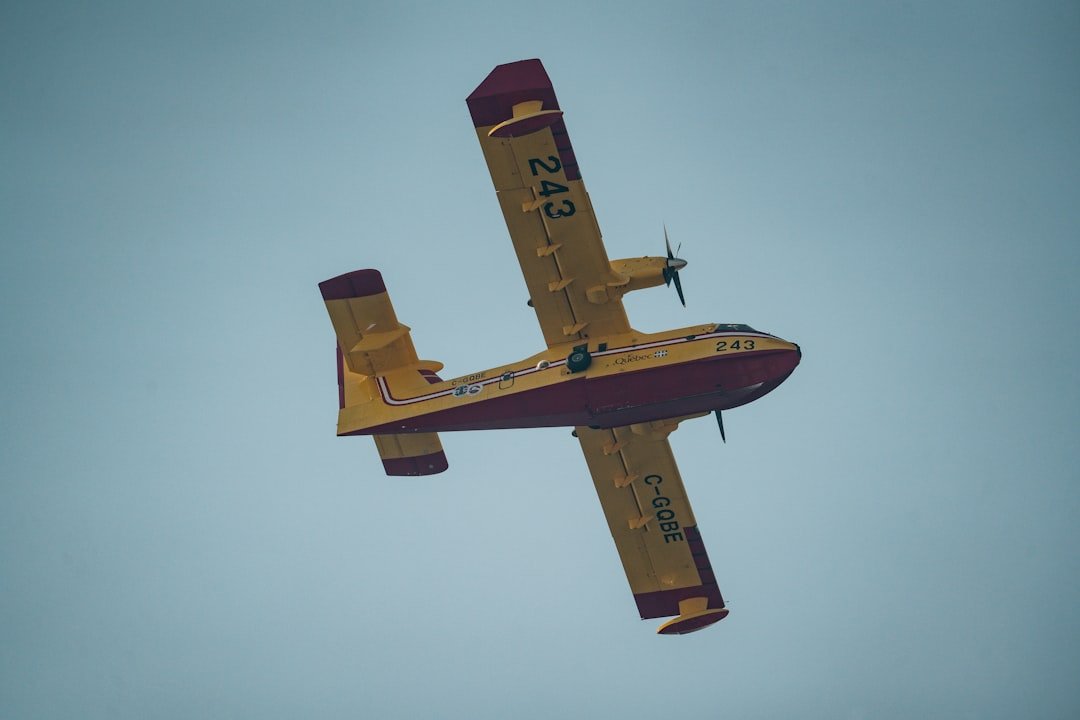 A small yellow airplane flying through a blue sky