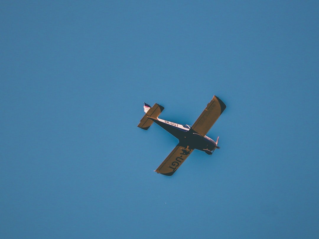 A small airplane flying through a blue sky