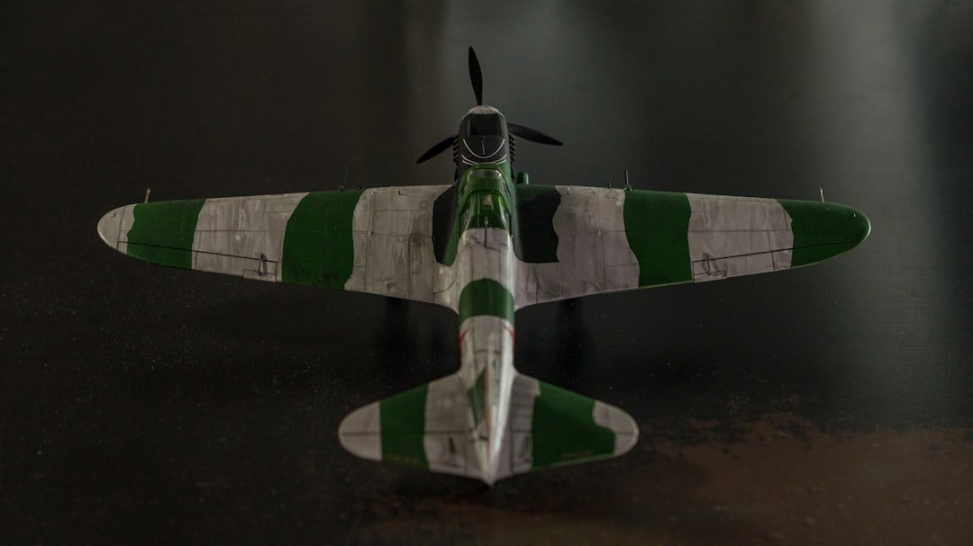 a small green and white airplane on a black surface