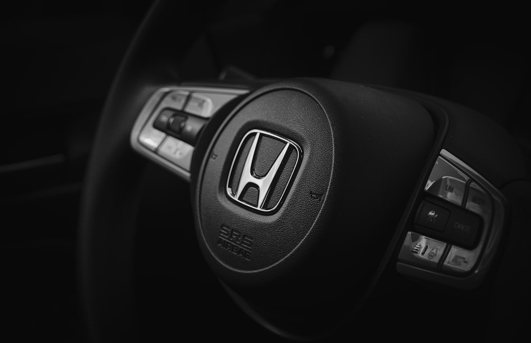 the steering wheel of a honda car in a black and white photo