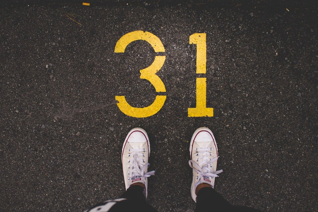 person standing beside 31 painted gray concrete road at daytime