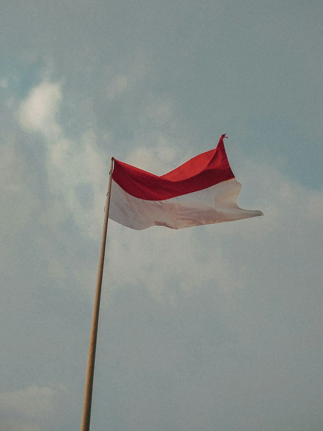 red and white flag under white clouds