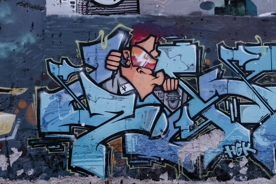 a man holding a cell phone in front of a graffiti covered wall