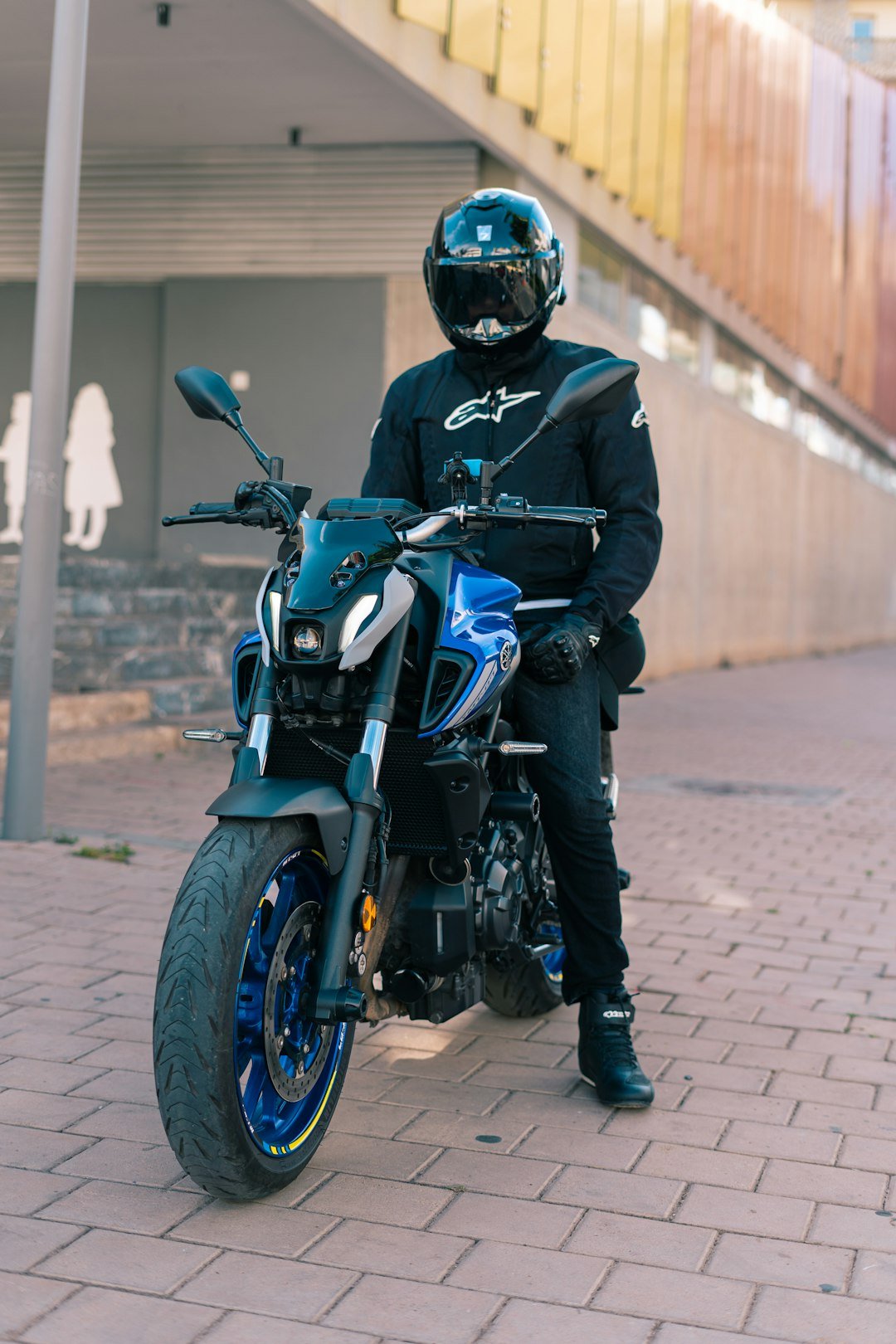 A person sitting on a motorcycle on a brick road