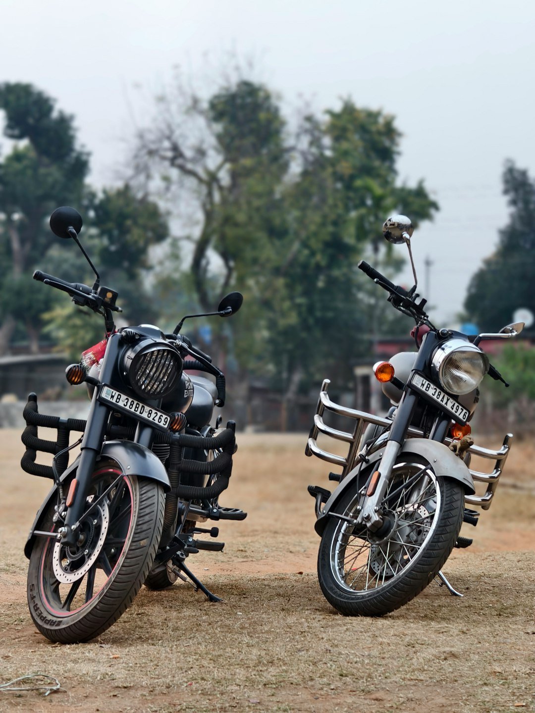 Two motorcycles parked next to each other on a dirt field
