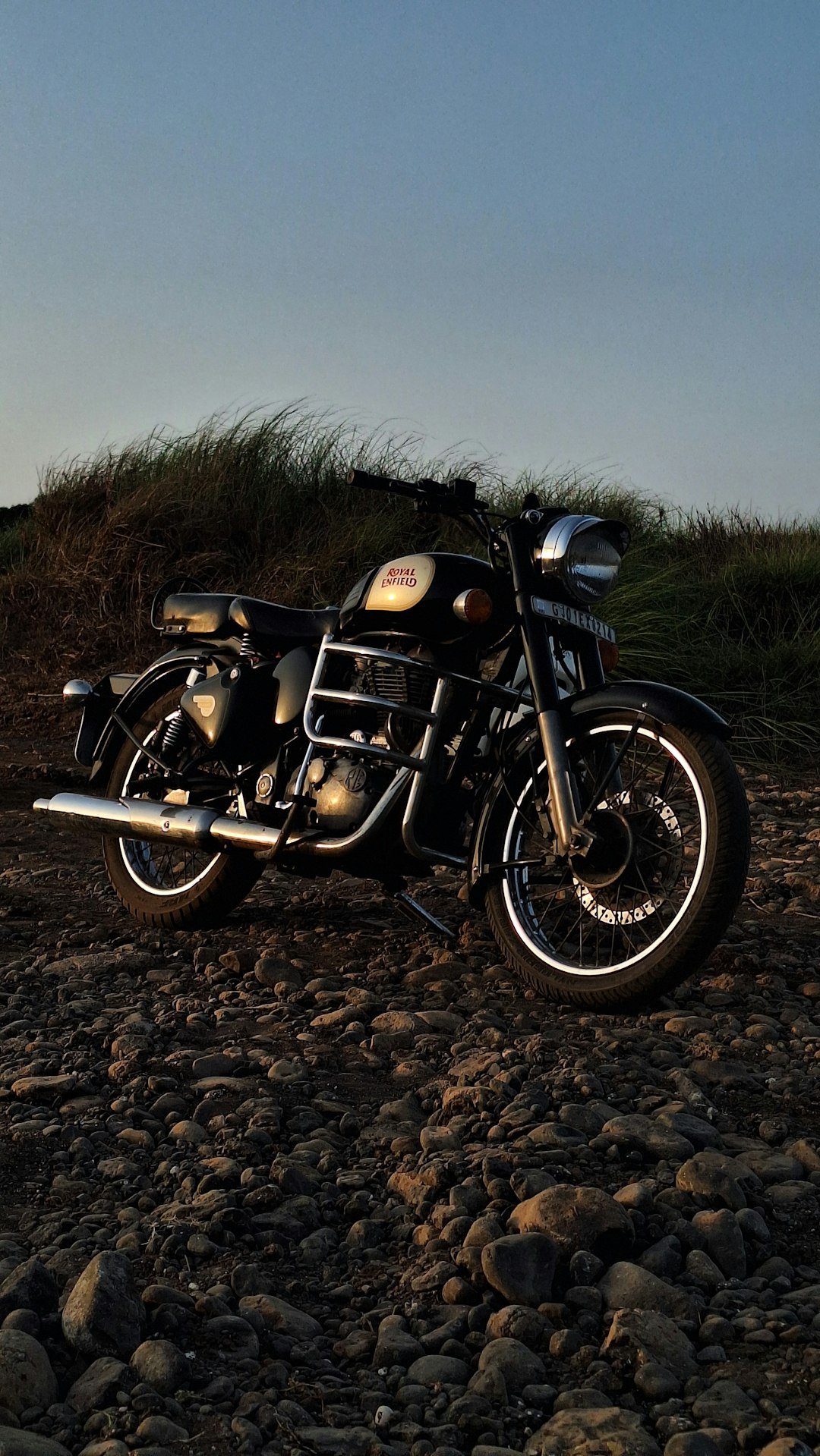 a black motorcycle parked on a rocky road
