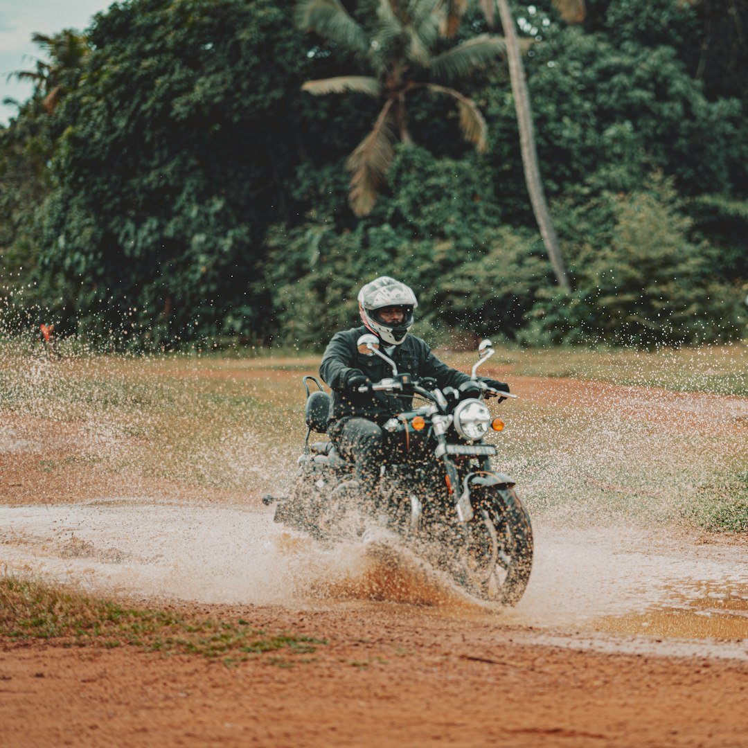 A man riding a motorcycle through a puddle of water