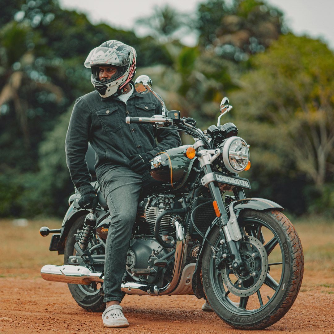 A man sitting on a motorcycle on a dirt road