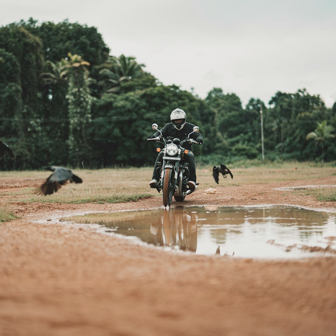 A man riding a motorcycle through a puddle of water