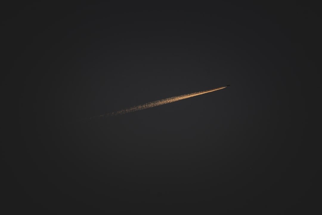 An airplane leaves a vapor trail in the dark.