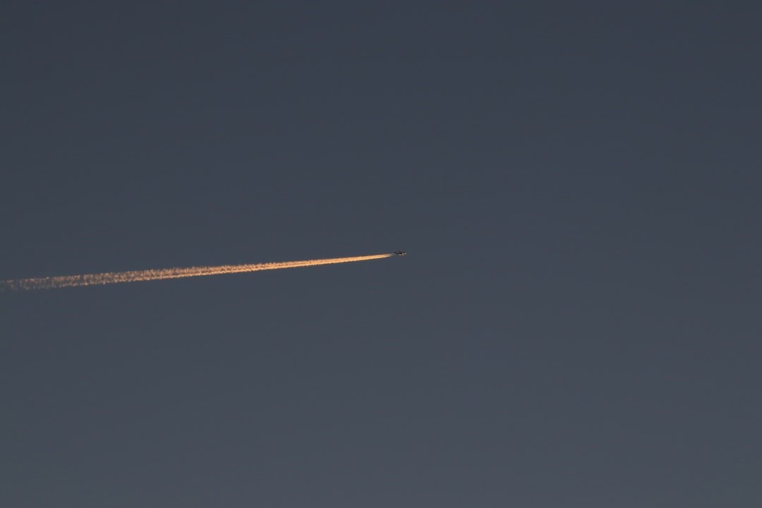 a jet flying through a blue sky with a contrail