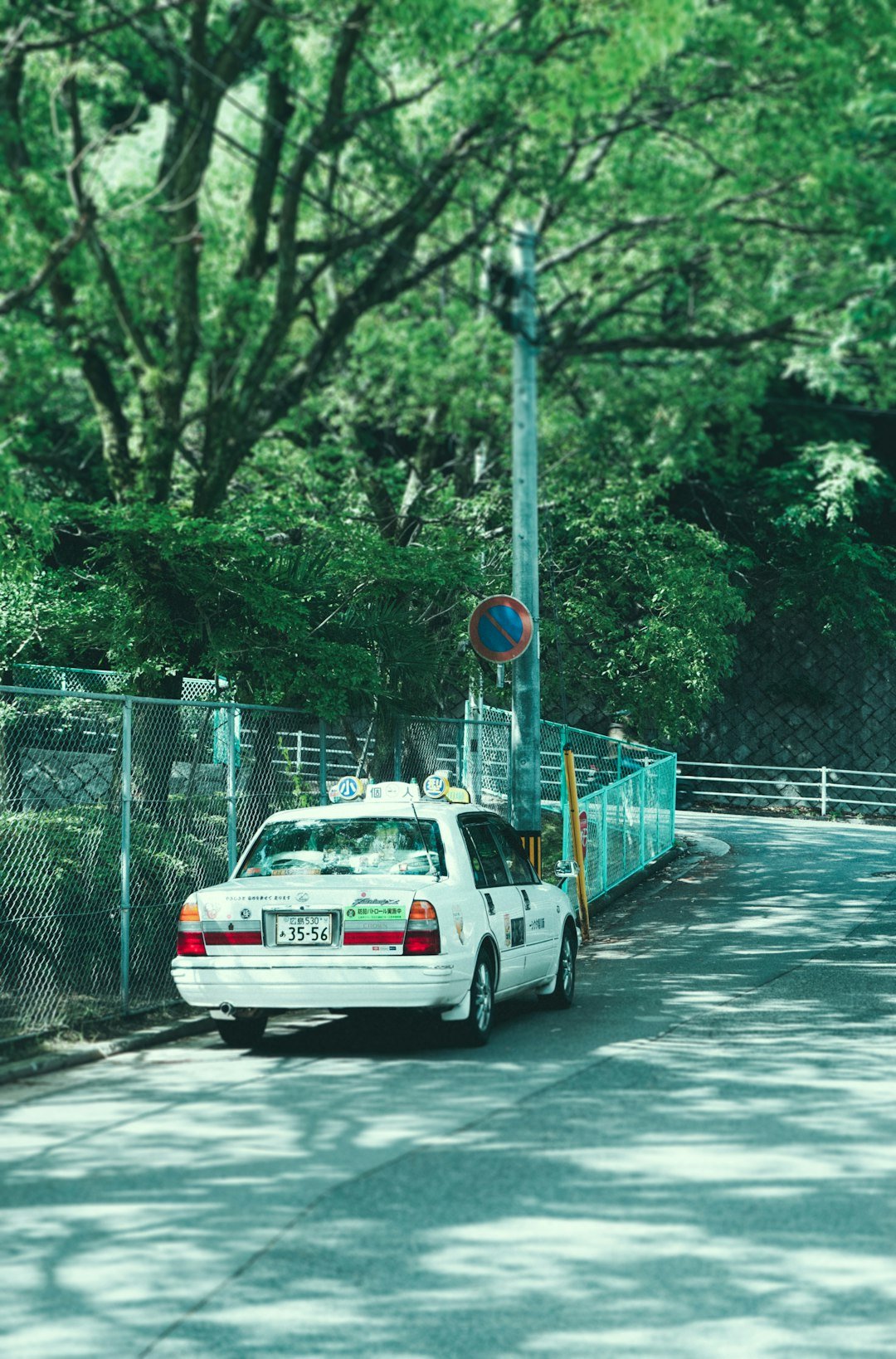 white taxi parked near grey metal fence