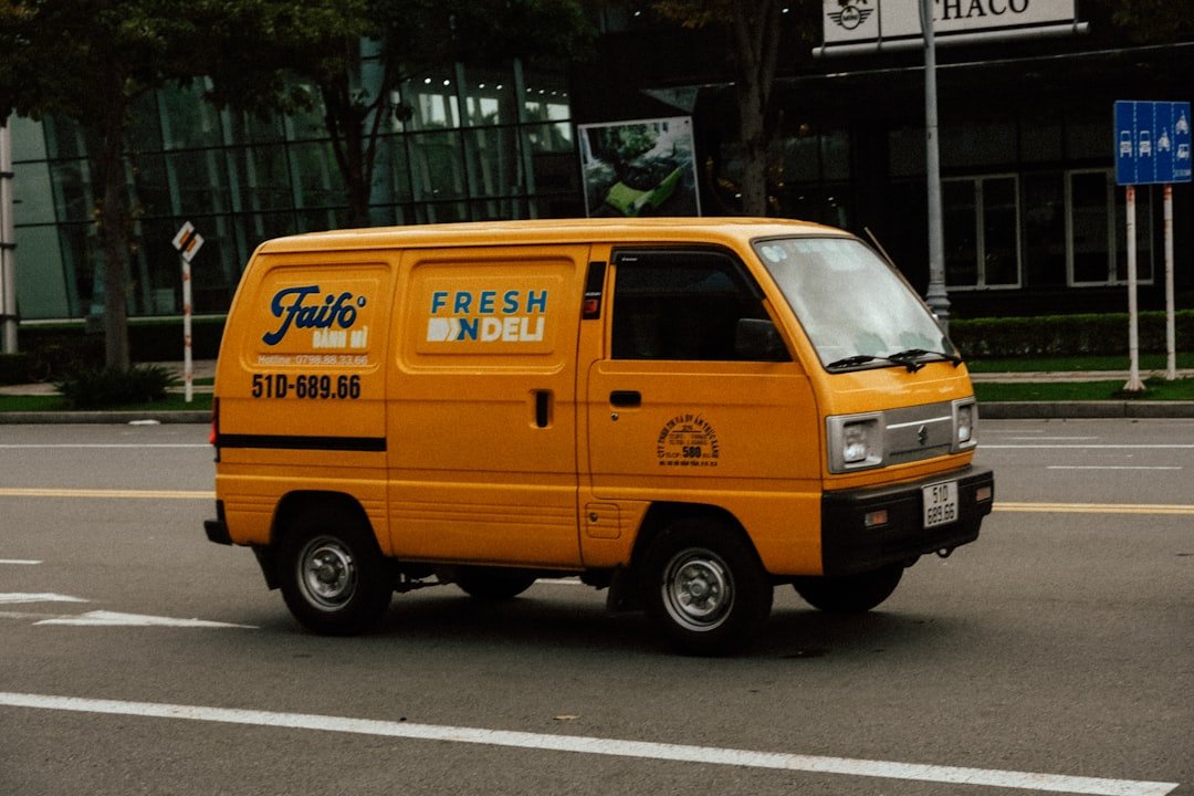 a yellow truck driving down a street next to a tall building
