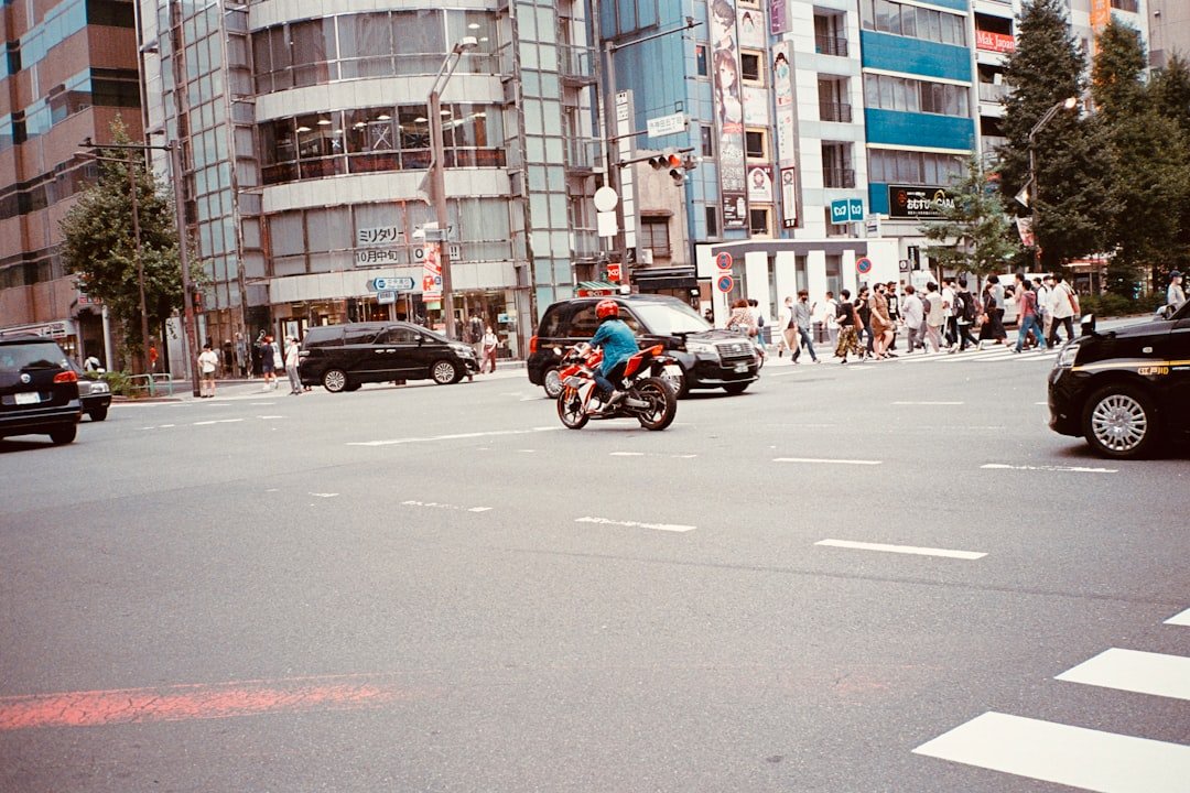 a man riding a motorcycle down a street next to tall buildings