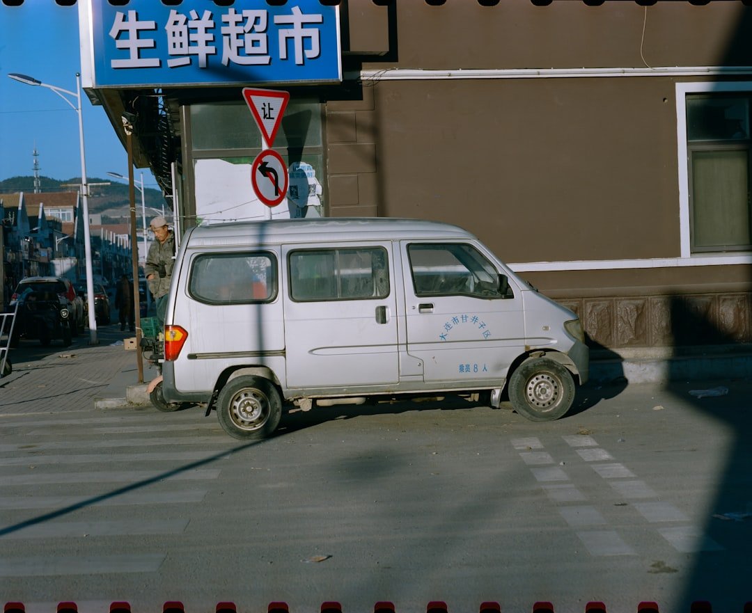 A small white van parked in front of a building