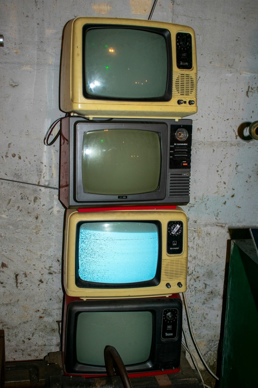 Four old television sets are stacked vertically.