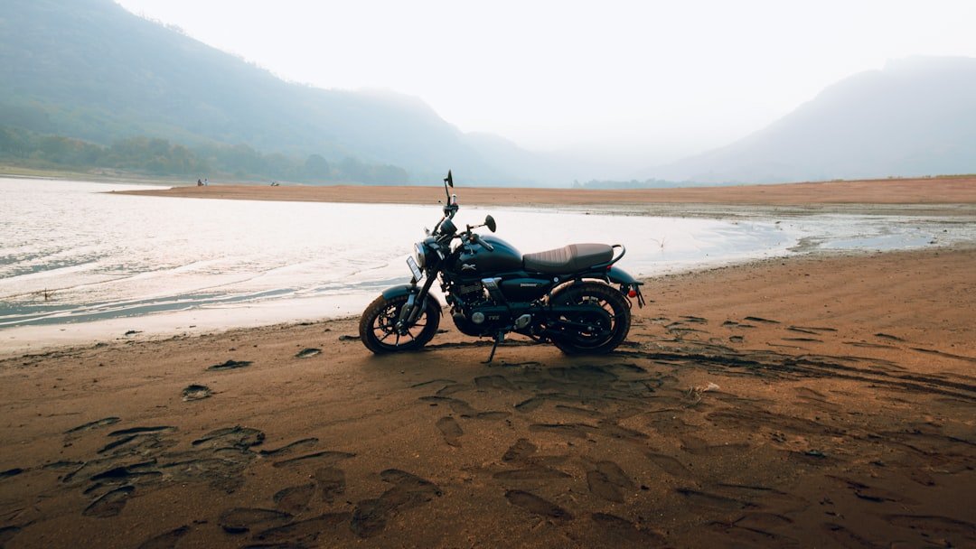 A motorcycle parked on a beach next to a body of water