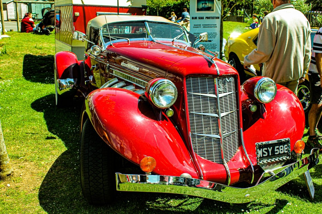 a red car parked on top of a lush green field