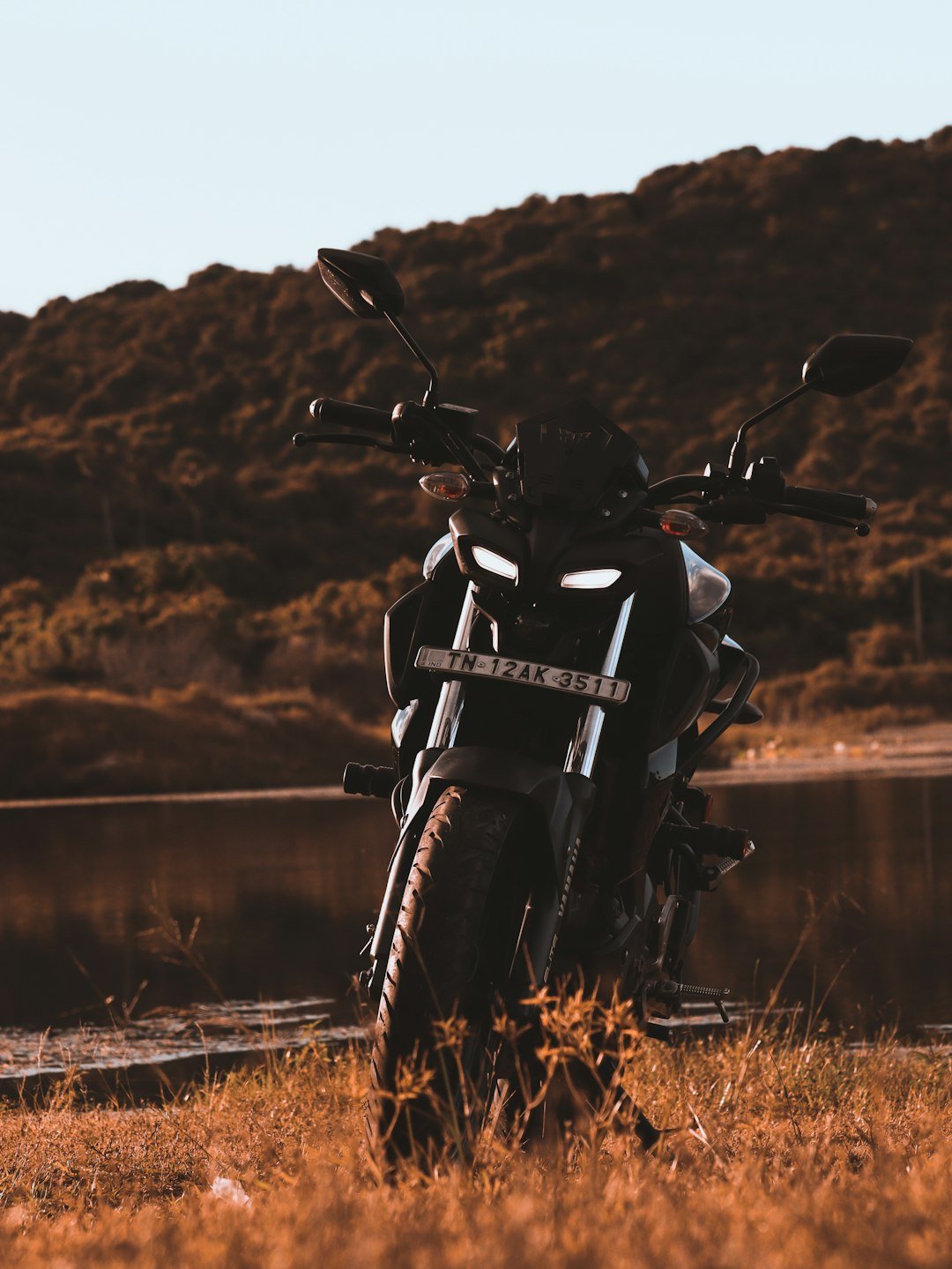 a motorcycle parked in a field next to a body of water