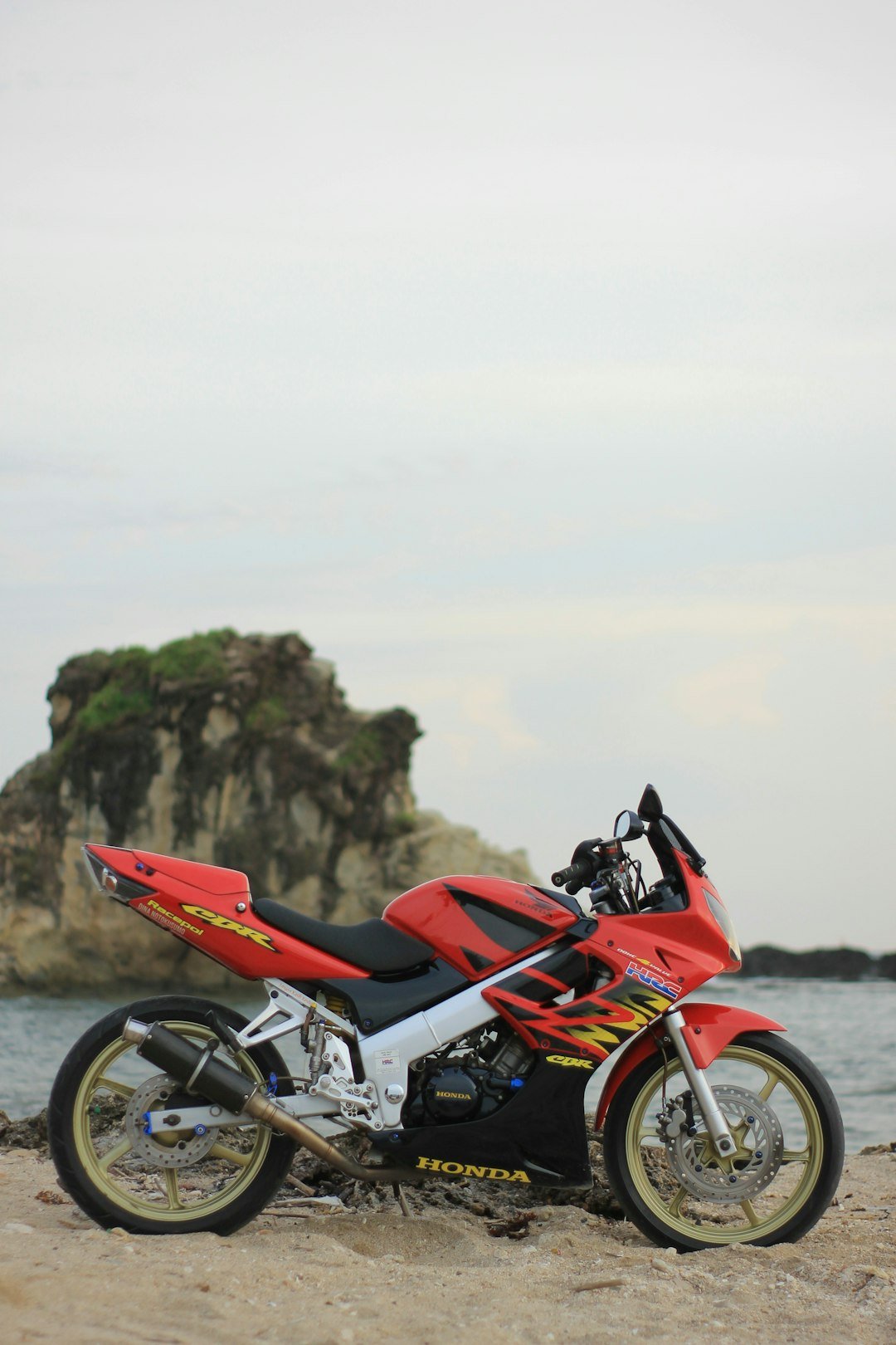 a red motorcycle parked on top of a sandy beach
