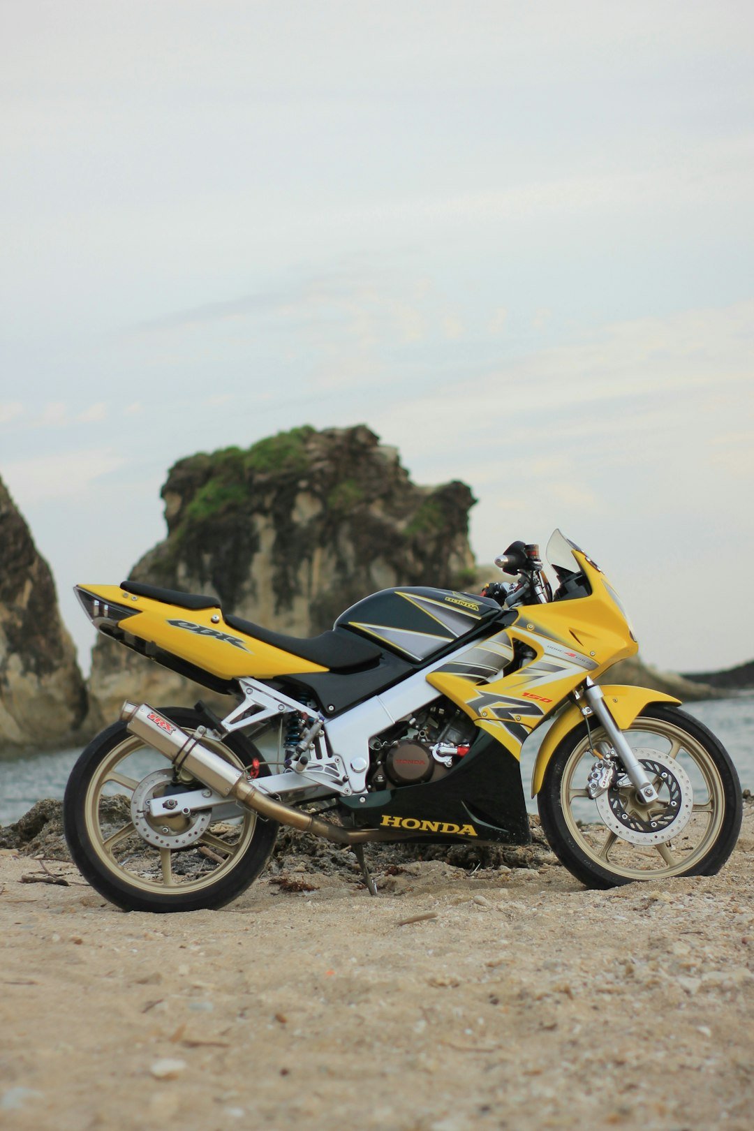 a yellow and black motorcycle parked on a beach
