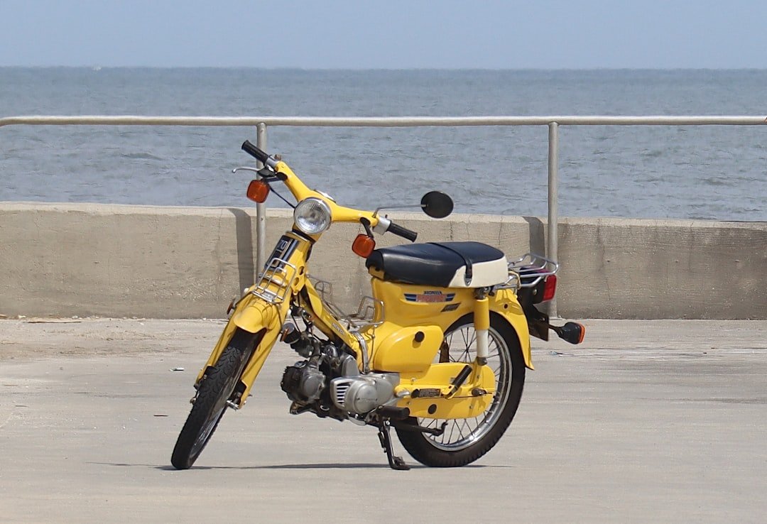 a yellow motorcycle parked next to the ocean